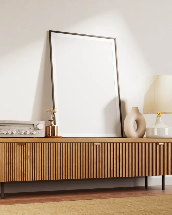 Personalisiertes Poster mit weißem Passepartout auf einem Sideboard, daneben Trockenblumen in einer Messingvase
